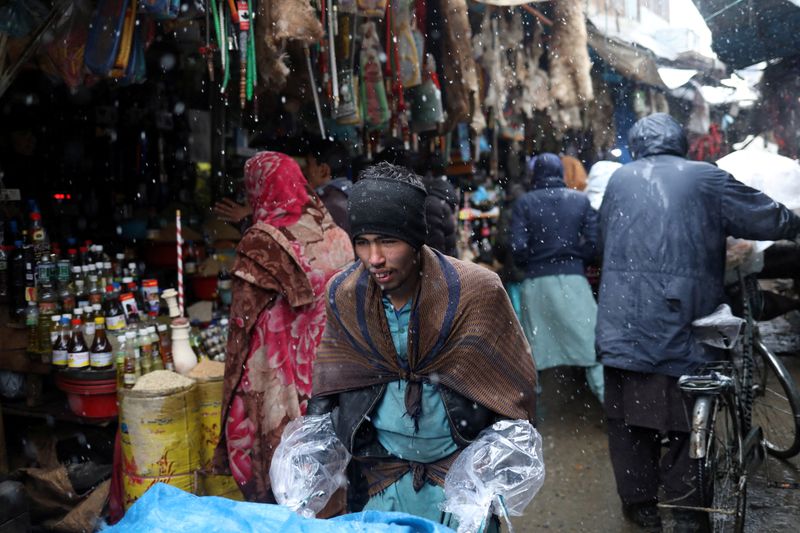 Afghan men walk in a market area during a snowfall