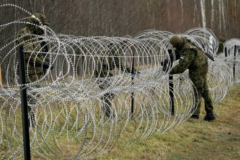 Estonian army reservists build a fence on a border with