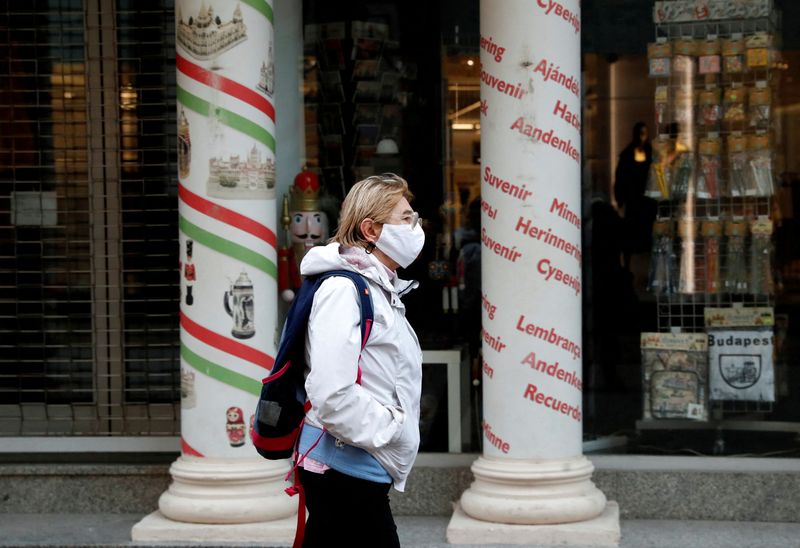 FILE PHOTO: A woman wearing a protective face mask walks