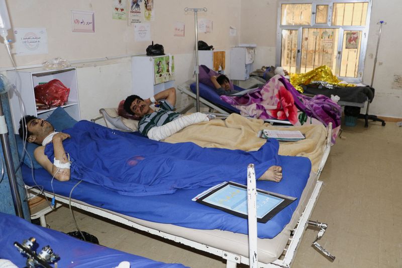 People injured by air strikes on a detention center lie
