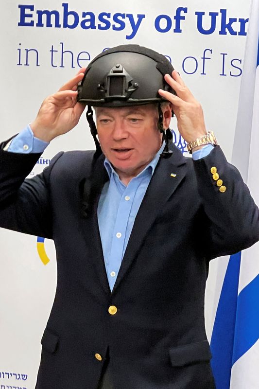 Ukrainian Ambassador to Israel Yevgen Korniychuk dons a helmet during