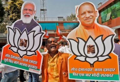A supporter of BJP displays cut-outs of PM Modi and