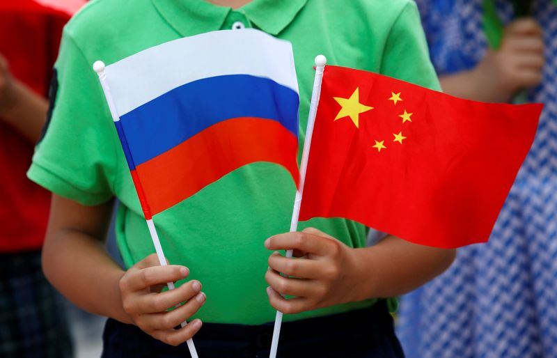 A child holds national flags of Russia and China prior