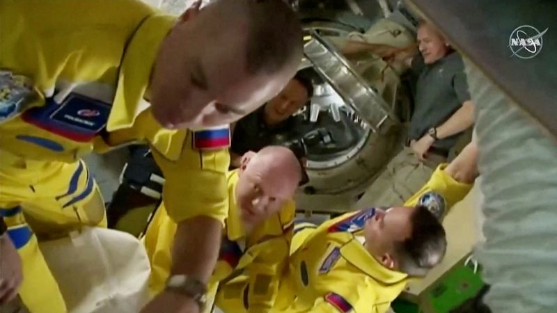Russian cosmonauts arrive wearing yellow and blue flight suits at