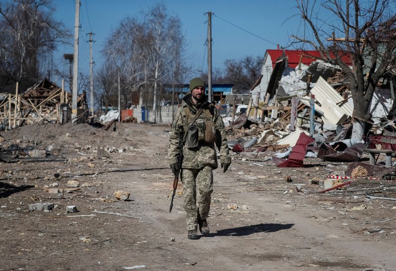Ukrainian service member walks in a destroyed village on the