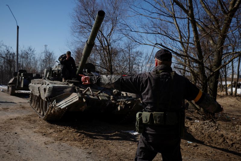 A Ukrainian soldier directs a Russian tank that Ukrainians captured