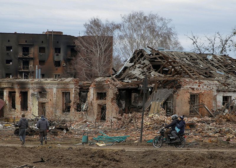 Local walks past buildings damaged by shelling in Trostianets