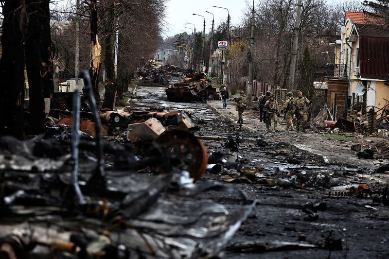 Soldiers walk past a destroyed Russian tank and armoured vehicles,