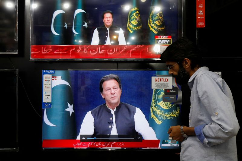 Shopkeeper tunes a television screen to watch the speech of