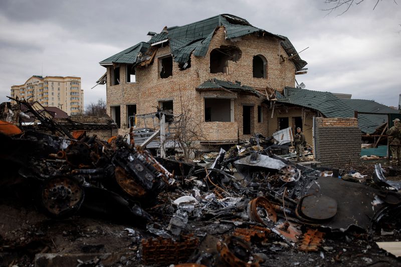 Ukrainian soldiers inspect a destroyed house, amid Russia’s invasion of