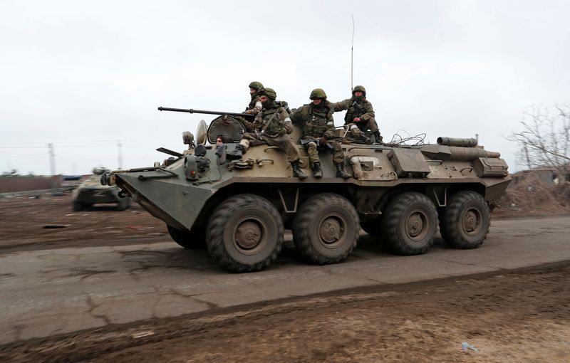 Service members of pro-Russian troops ride an armoured vehicle in
