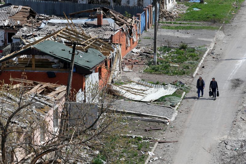 People walk near damaged buildings in Mariupol