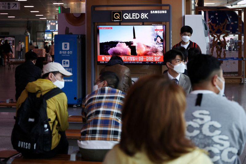 FILE PHOTO: People watch a television broadcasting a news report