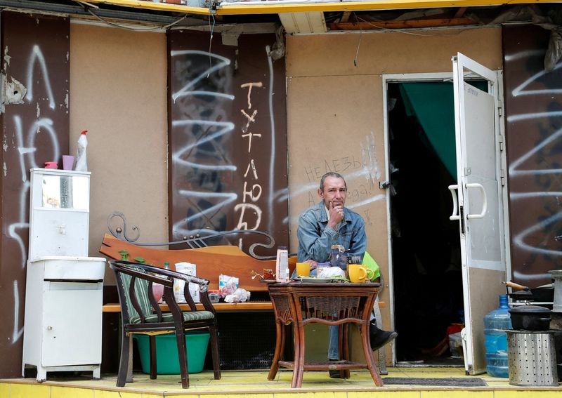 A local resident sits outside a damaged building in Mariupol