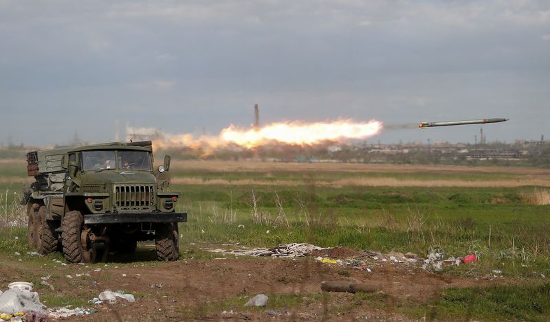 Service members of pro-Russian troops fire a BM-21 Grad multiple