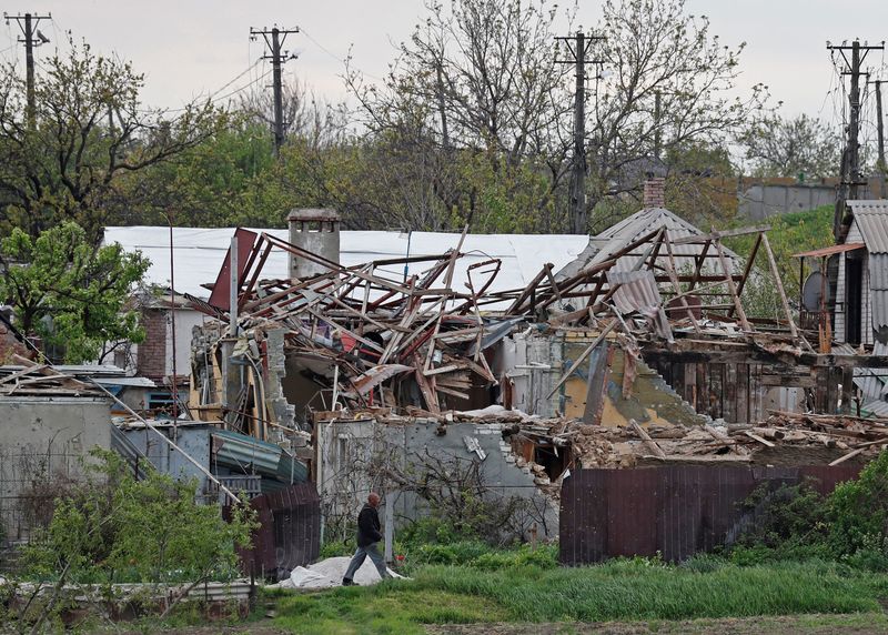 A local resident walks past destroyed houses in Mariupol