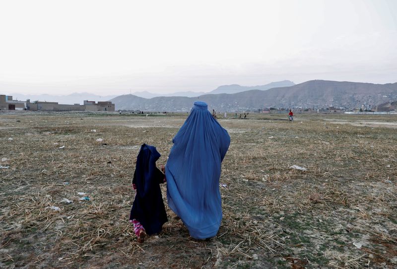 An Afghan woman clad in burqa walks in the early