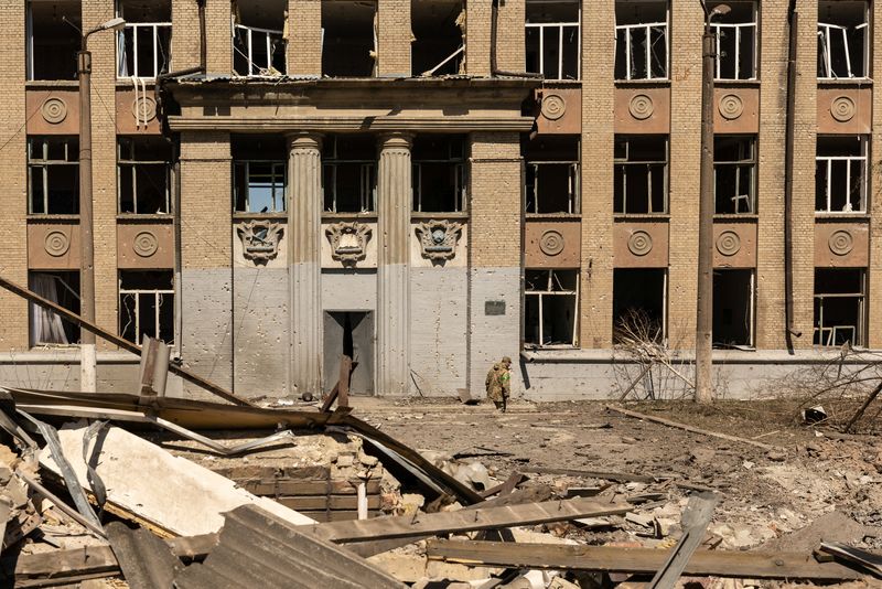 A Ukrainian soldier walks in front of a school that