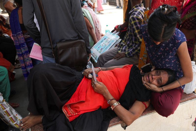 Woman consoles her mother as they wait to identify Komal’s