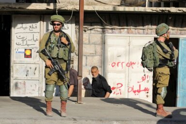 Israeli soldiers stand outside a Palestinian shop in Huwara