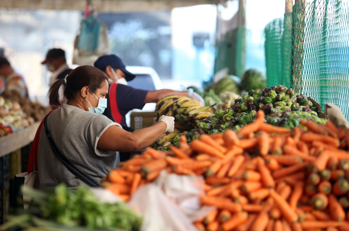 A woman wearing a protective mask picks vegetables in a