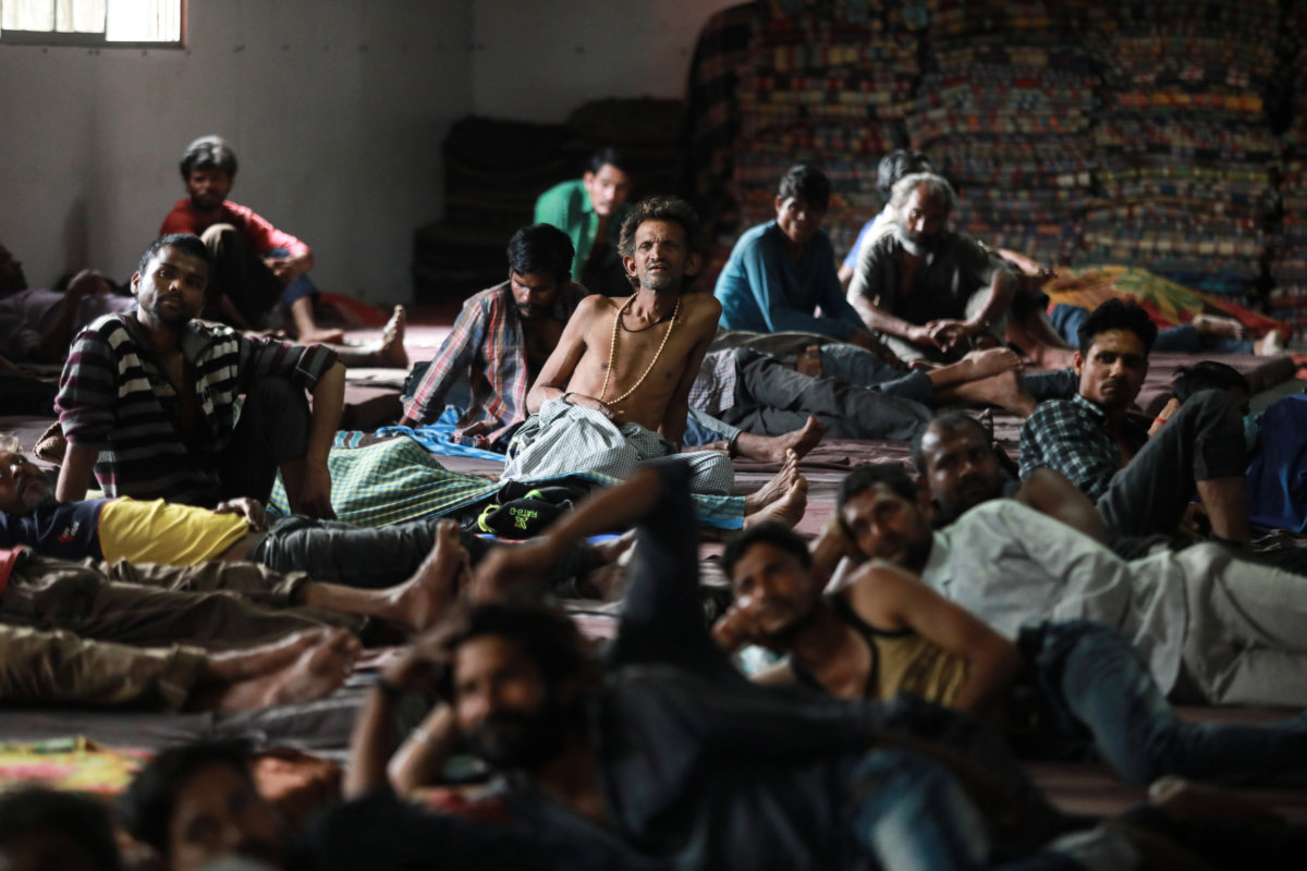 Daily wage workers and homeless people watch television inside a