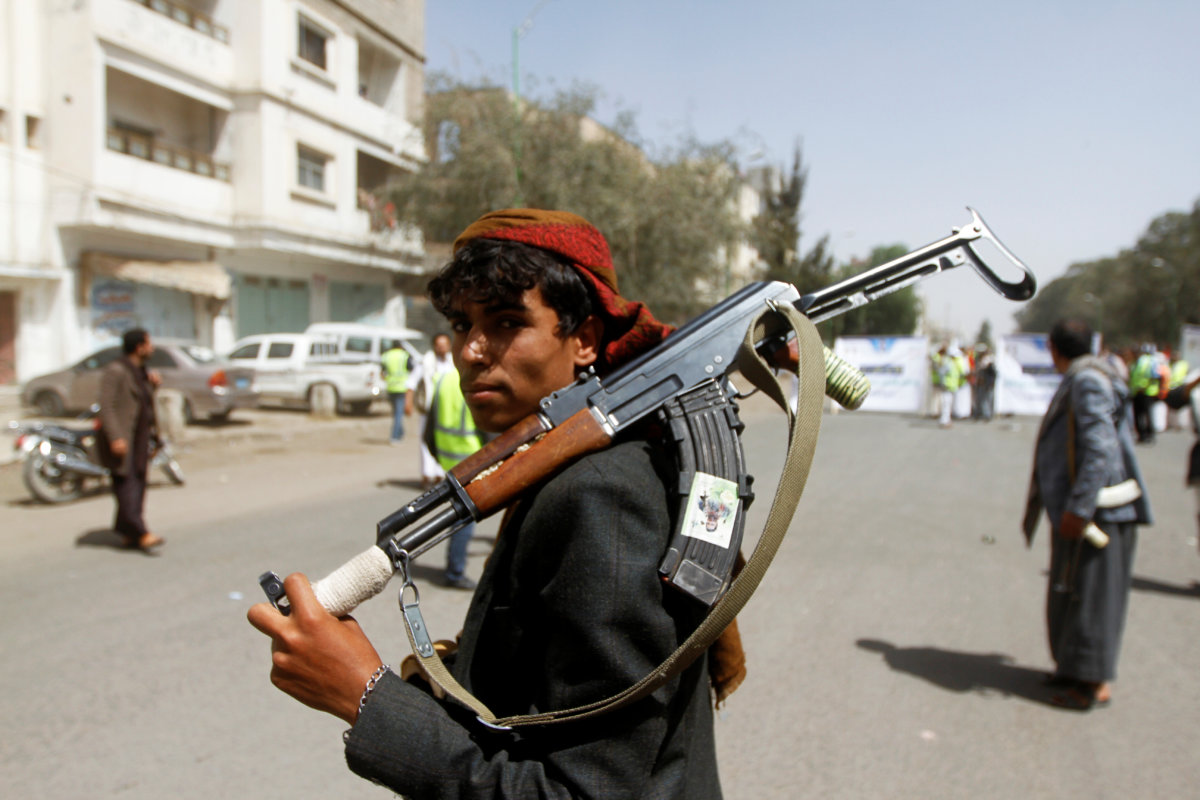 A Houthi supporter looks on as he carries a weapon