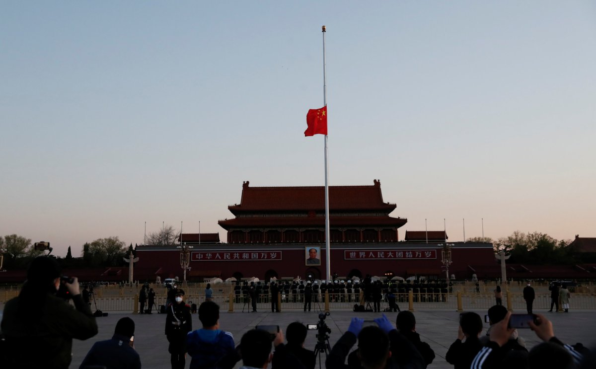 The Chinese national flag flies at half-mast during sunrise at