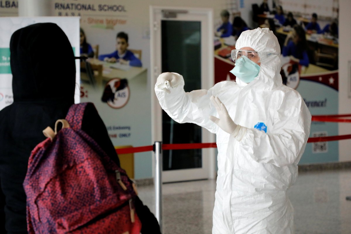 Medical staff member, wearing protective suit, gestures at Tirana International