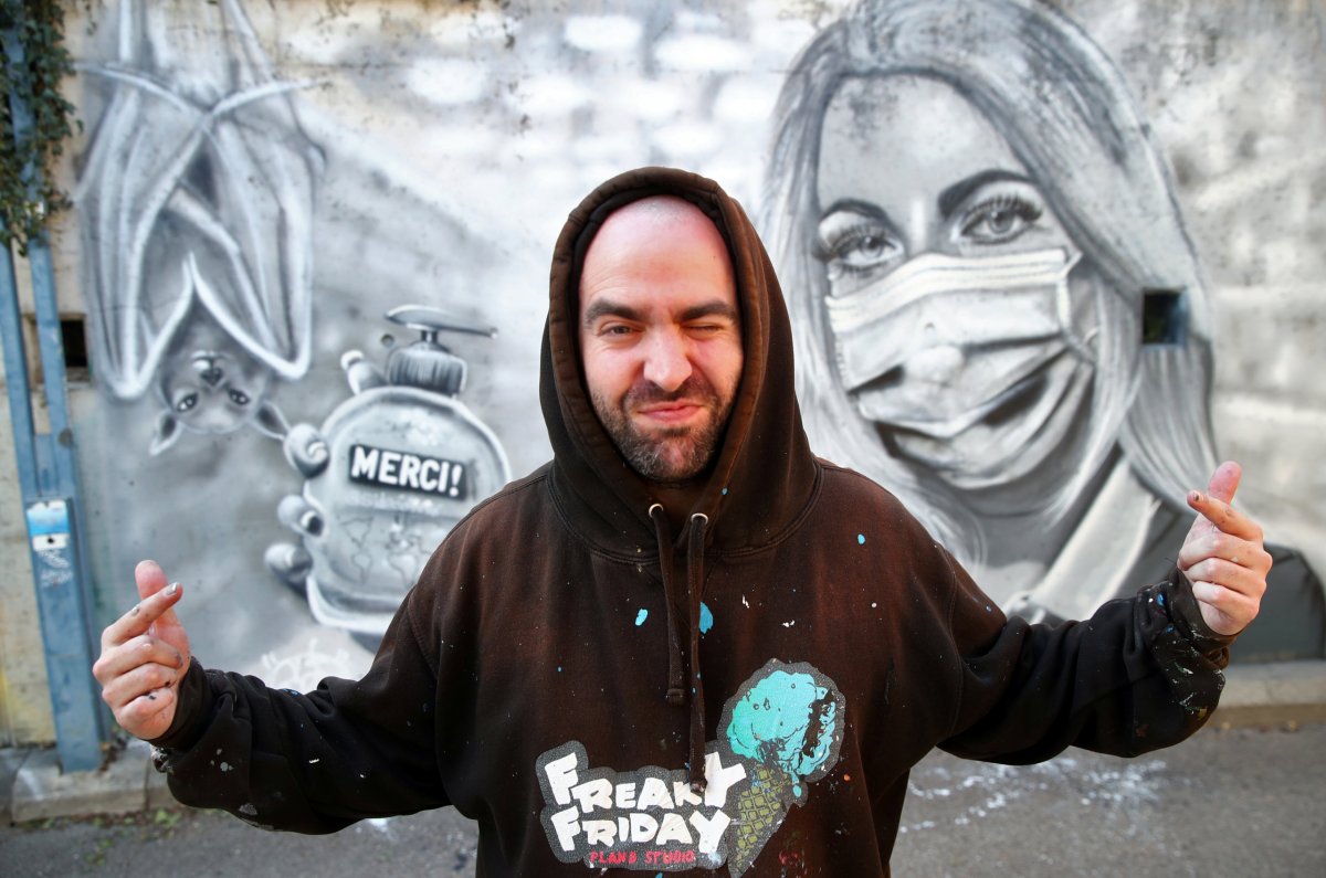 Artist Perez takes poses in front of his graffiti of