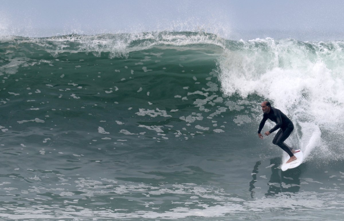 A surfer rides a wave on Copacabana beach, amid the