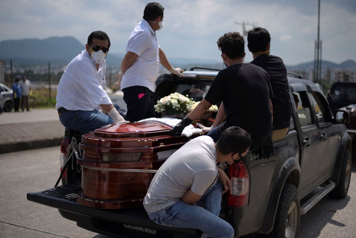 People wait next to a coffin in a pick-up truck