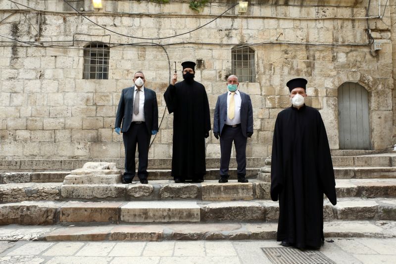 Orthodox Christian clergymen and church officials wearing face masks stand