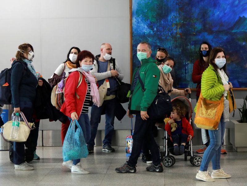 FILE PHOTO:  Passengers wearing protective masks arrive to collect
