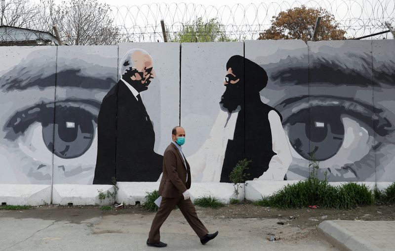 An Afghan man wearing a protective face mask walks past