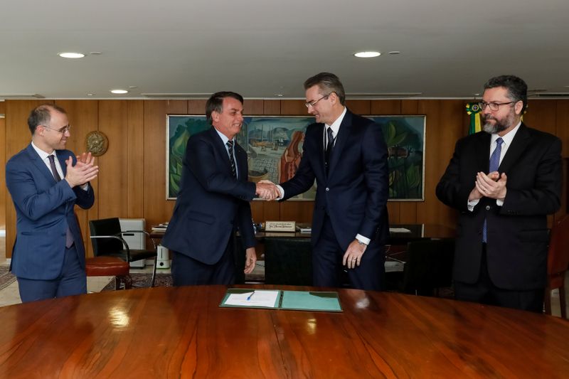 Brazil’s President Jair Bolsonaro shakes hands with Rolando Alexandre de