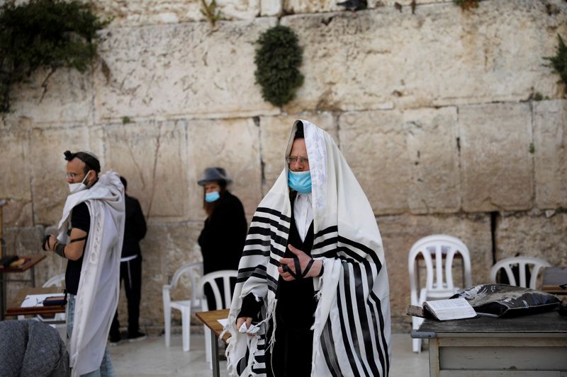 Jewish worshippers wear face masks as they pray by the