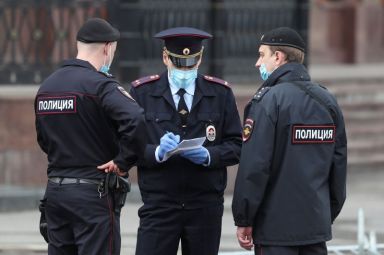 Police officers wearing protective face masks speak in a street