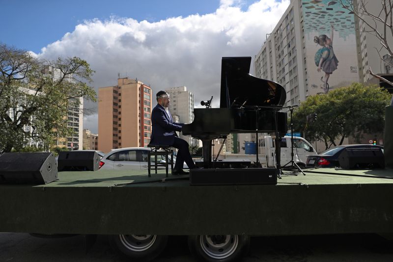 Pianist Rodrigo Cunha serenades from an open truck, in Sao
