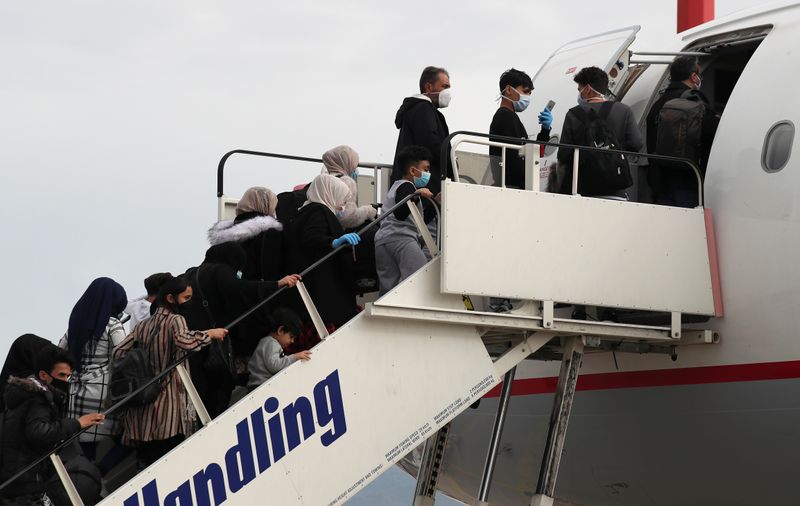 Refugees and migrants board their flight to Britain at the