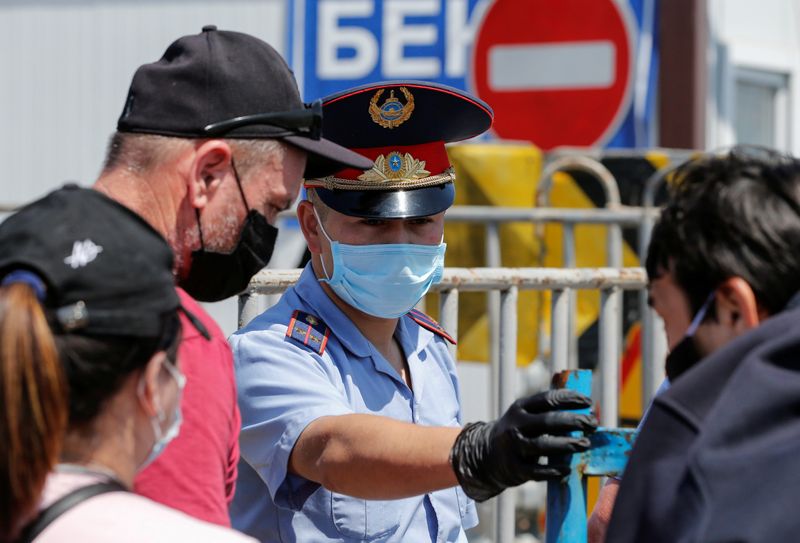 A police officer wearing a protective mask directs local residents