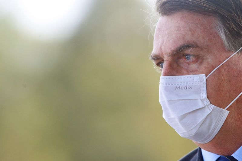 Brazil’s President Jair Bolsonaro wearing a protective face mask looks
