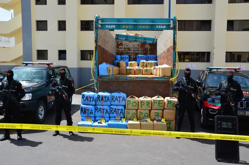 Police officers stand guard near packages of seized cannabis at