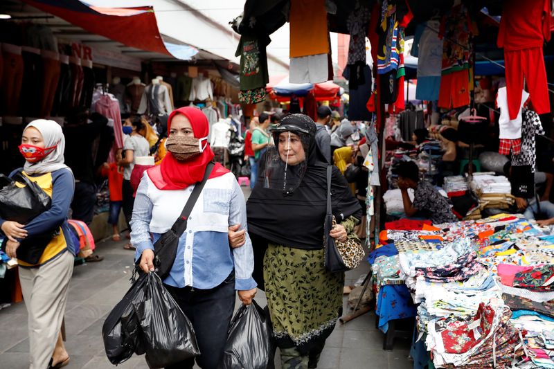 Women wearing protective face masks and a face shield walk