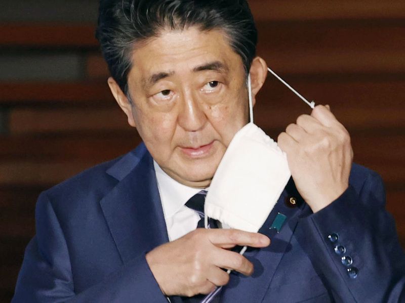 Japan’s Prime Minister Shinzo Abe taking off his face mask