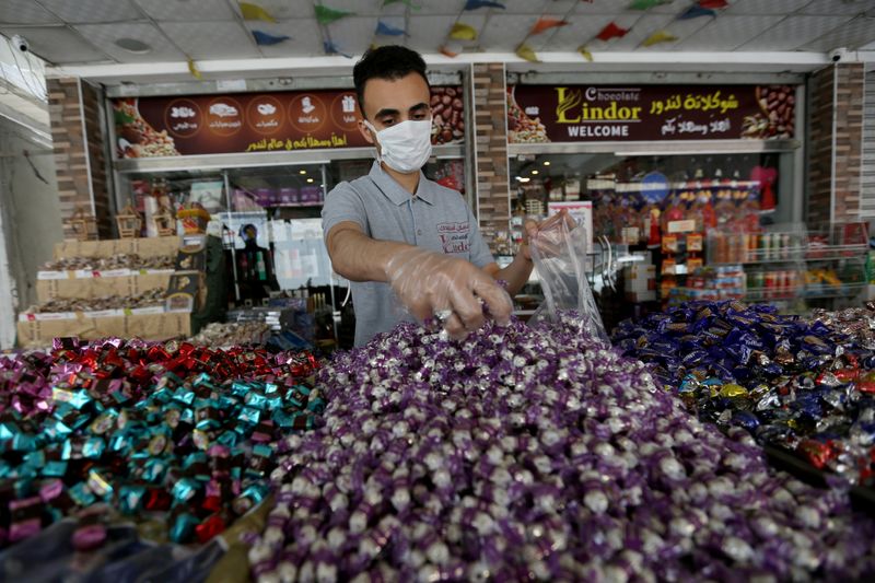 A worker packs sweets outside a shop as Palestinians prepare