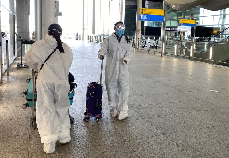 Passengers wearing protective clothing are seen at Heathrow Airport, London