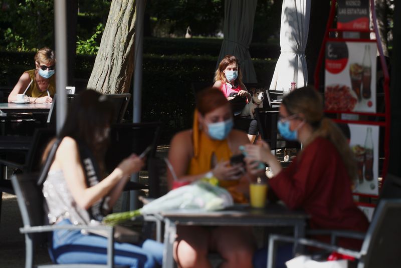 People wearing face masks sit at an outdoor seating section