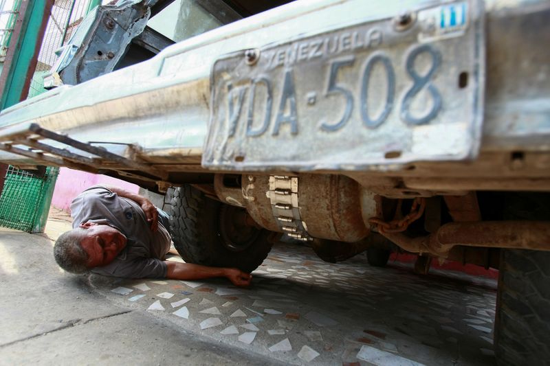 Alfredo Gonzalez checks a cooking gas canister beneath his car,