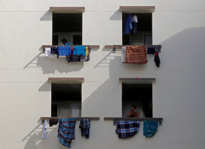 FILE PHOTO: Migrant workers look out of windows in a